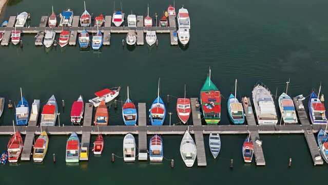 Drone bird's eye view pan across colorful boats docked at fishing harbor pier in Caribbean