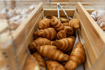 Lots of fresh croissants on a wooden counter in a store. Delicious crispy pastry for breakfast....