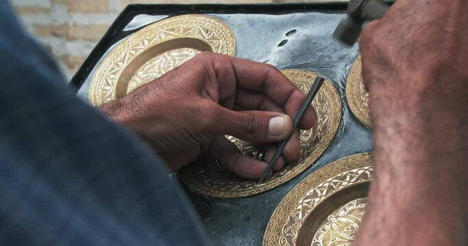 A master embosser creates a pattern on a copper plate using ancient technologies.