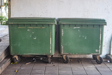 two large green trash cans that have wheels