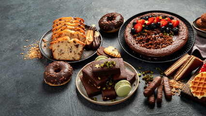 Tasty cake, cookies, waffles, macaroons, muffin. Delicious desserts on dark background. Food concept