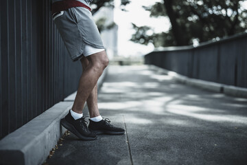 A man stand on footbridge after running in the city center park before cardio workout.  Health and...