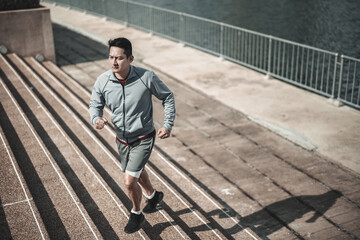 A man  running up on stairs in the city center park for cardio workout.  Health and Lifestyle in...