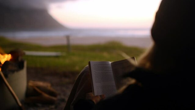 Person, camping and sunset with reading book, travel and back on holiday by the beach an coast. Calm, relax and ocean with adventure trip and vacation outdoor with sunrise and freedom in nature