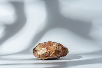 Piece of granite stone on white background with shadows