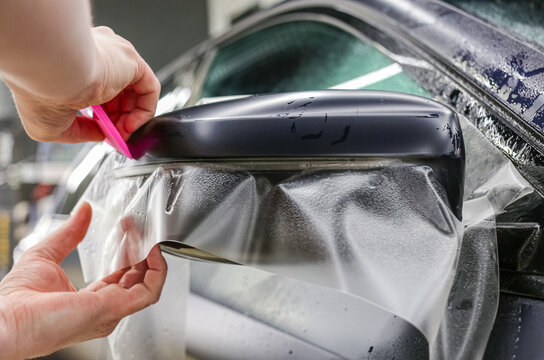 The process of installing PPF on the side mirror. The process of installing PPF on the car. PPF is a polyurethane, protective film that protects the paint from scratches and gravel.  Car wrapping. 
