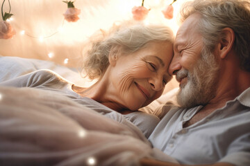 An elderly couple in love, a man and a woman, are lying in bed. Love and romance. Family idyll. Happy morning for lovers. Valentine's Day.