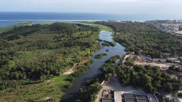 Wide revealing drone footage of the Reserva Ecologica municipal Estero in San Jose del Cabo Baja California Sur Mexico, wetlands and maritime forest with the ocean in the distance