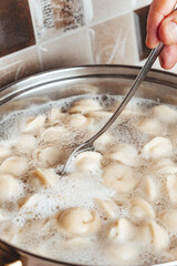 Dumplings are boiled in a pot of boiling water. Close-up.