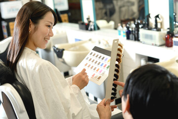 美容室でヘアカラーを選ぶアジア人の女性客