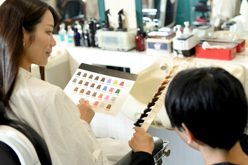 美容室でヘアカラーを選ぶアジア人の女性客