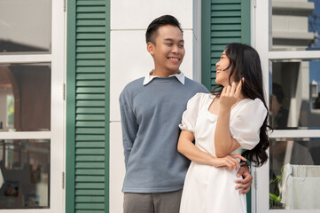 Fototapeta premium Young beautiful Asian couple standing in front of their house, having a good time together.