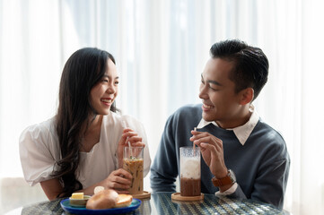Adorable cute Asian couple having a lovely date at a cafe, having food and drinks.