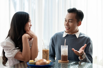 Adorable cute Asian couple having a lovely date at a cafe, having food and drinks.