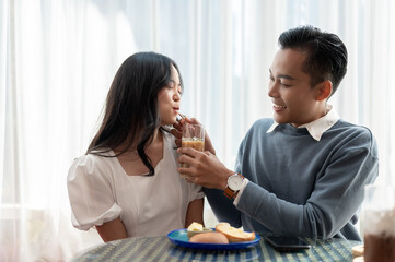 Adorable cute Asian couple having a lovely date at a cafe, having food and drinks.