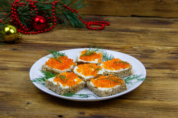 Canapes with red caviar and Christmas decorations on wooden table