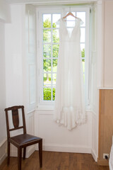 Robe de mariée suspendue devant une fenêtre