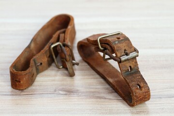 Old leather straps used to tie up skis togetner. Natural leather belts from last century on wooden...