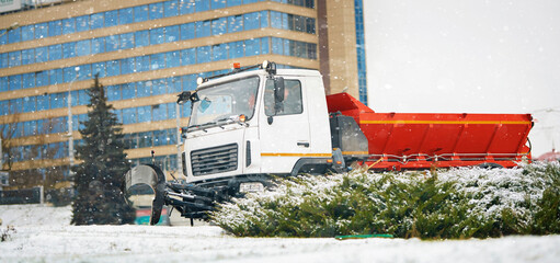 Truck removing snow in the city during blizzard. Cleaning vehicle clears the snow from the street in winter. Winter snowplow truck removing snow. Snowplow at work.