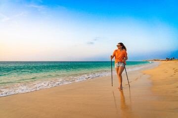 Nordic walking - beautiful woman exercising on tropical beach, Santa Maria, Sal Island, Cape Verde
