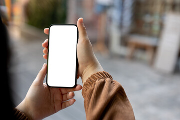 A woman holding a white-screen smartphone mockup over a blurred background of a city.