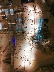 Aerial view of an outdoor ice-skating rink in Tallinn's Old Town, illuminated by festive lights against the night's snowy canvas.