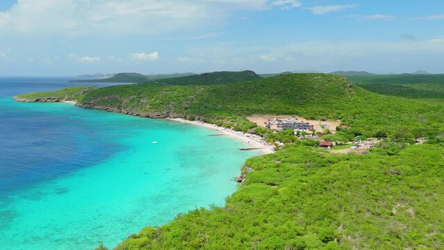 Panoramic aerial dolly above Playa Porto Mari as clouds cast shadow on water and land below