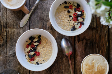 Oatmeal with raisins, dried cherries and almond petals. wooden background, side view