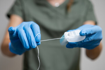 Oral thread or dental floss held by a dental professional wearing rubber gloves. 