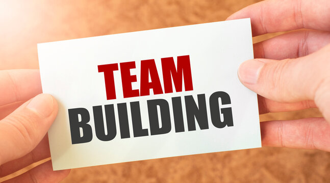 TEAM BUILDING word inscription on white card paper sheet in hands of a businessman.