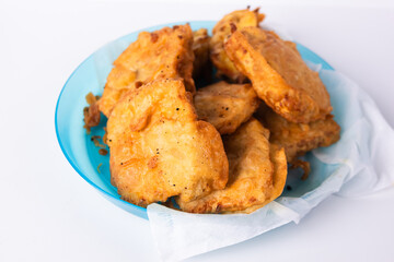 Flour fried tempeh on a blue plastic plate isolated on a white background