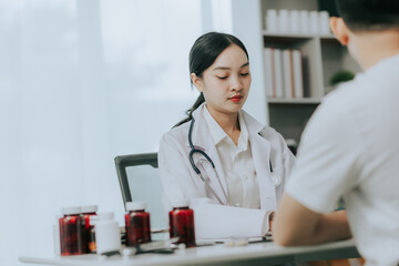 Asian female doctor discussing medicine bottle with male patient in hospital