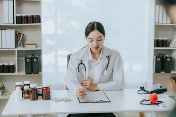 Asian female doctor sitting and working in office space Analyze and examine medicines within the...