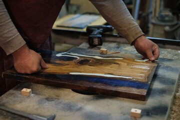 The focus and precision of a carpenter are evident as he sands down a wooden board, immersed in the...