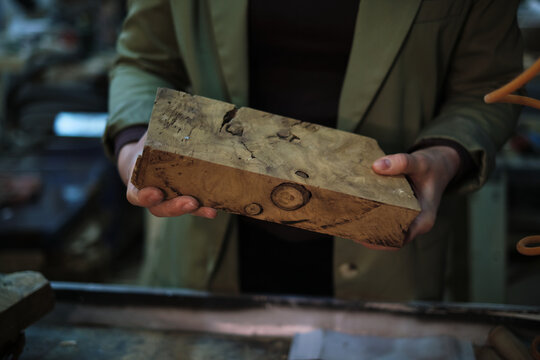 A woodworker’s hands carefully assess a piece of burl, where the swirls and knots speak of the wood’s journey from nature to craft. - Powered by Adobe