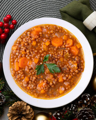 Lentils with chorizo ​​and black blood sausage. Christmas food served on a table decorated with Christmas motifs.