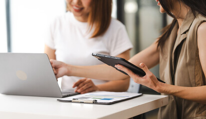 Two Asian colleagues, freelance writer and graphic designer discussing about creating characters in...