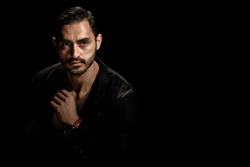 Portrait of young fashionable bearded man isolated on black background, Dramatic low-key portrait of a young man with a dark ambiance, showcasing his beard