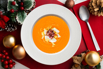 Traditional spanish salmorejo. Cold tomato soup served with egg and iberico jam. Christmas food served on a table decorated with Christmas motifs.