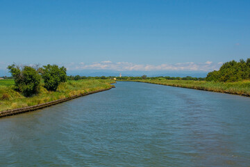 A navigable channel near Aquileia in the Grado section of the Marano and Grado Lagoon in Friuli-Venezia Giulia, north east Italy. August - obrazy, fototapety, plakaty