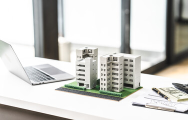 Model buildings on a desk next to a laptop, symbolizing city real estate investing and large building developments.