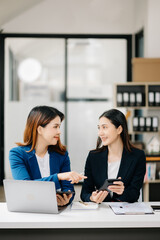 Asian business colleague business presents and explains and using laptop and tablet. Teamwork, financial marketing team