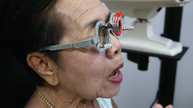 Using a trial frame, elderly is having her eyes checked manually in an optical shop in Bangkok, Thailand.