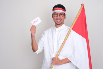 Indonesian man smiling confident while holding presidential election vote card