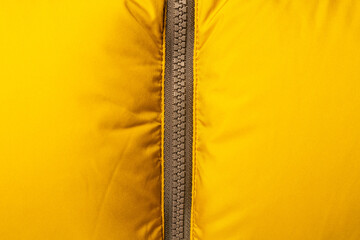 Zipper of a yellow down jacket close-up