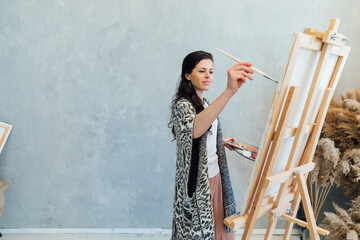 The artist emotionally paints a picture on an easel in the studio