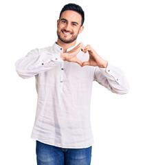 Young handsome man wearing casual clothes smiling in love showing heart symbol and shape with...