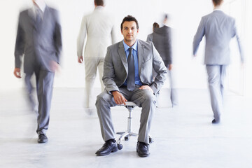 Portrait, chair and a business man in a busy office with motion blur people walking for corporate...