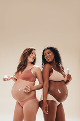 Pregnant women smiling and applying self care belly cream for prenatal wellness