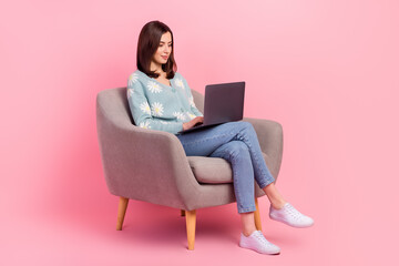 Full length body photo of concentrated young assistant woman work remote sitting armchair with laptop isolated on pink color background